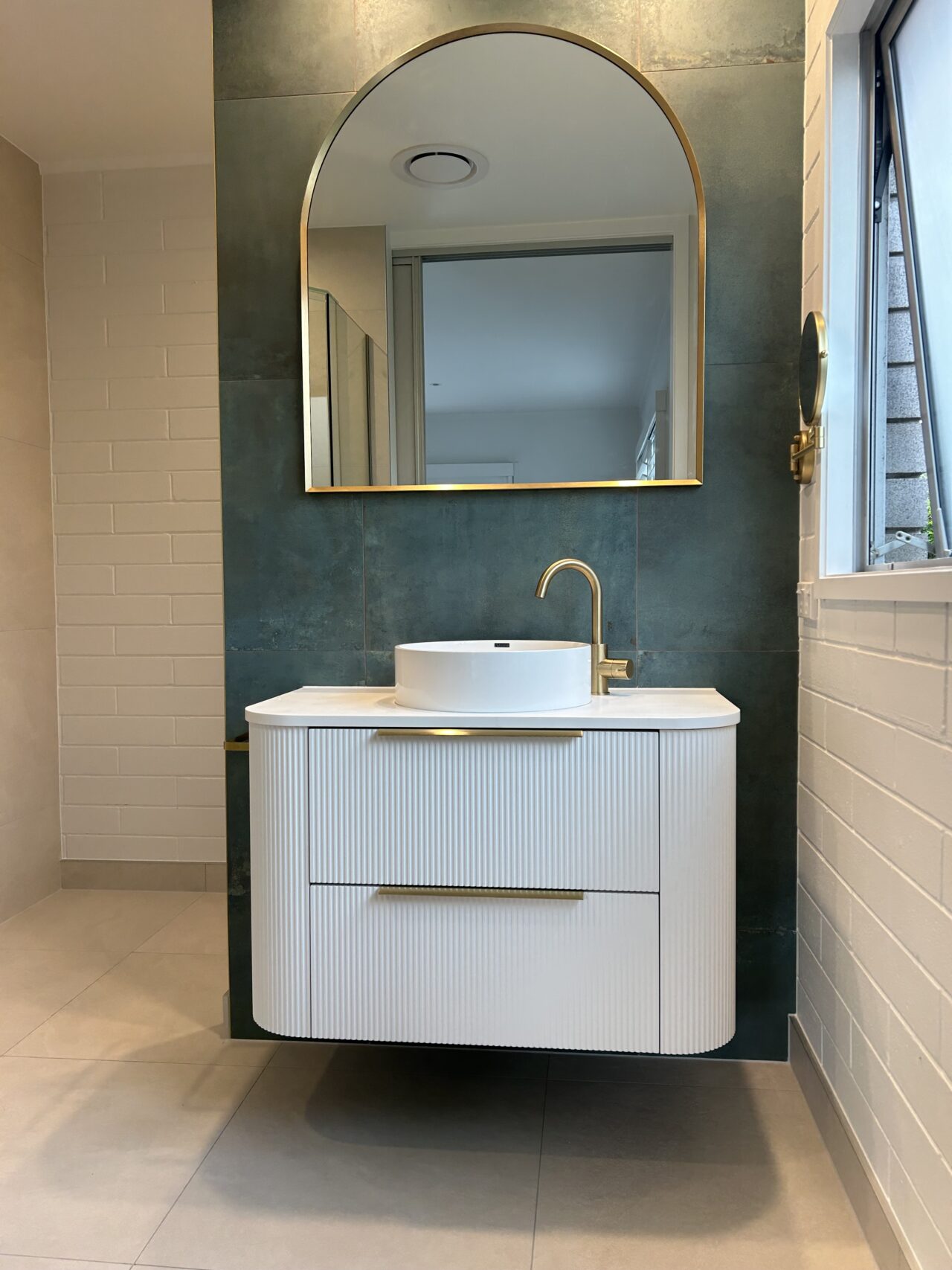 Modern bathroom vanity with brass tapware and tiled feature wall