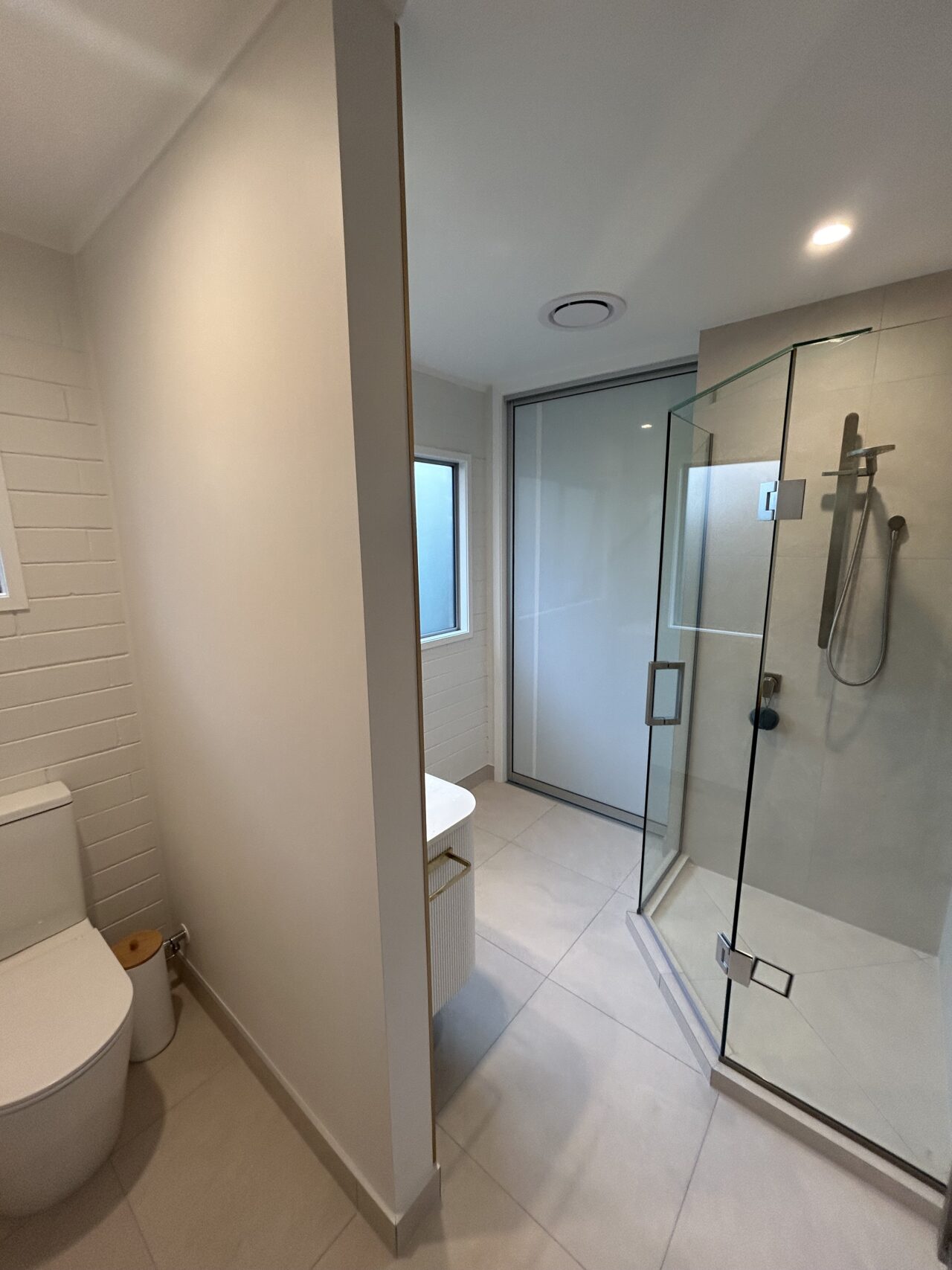Luxury bathroom with tiled shower enclosure, frameless glass panels, and brass fixtures